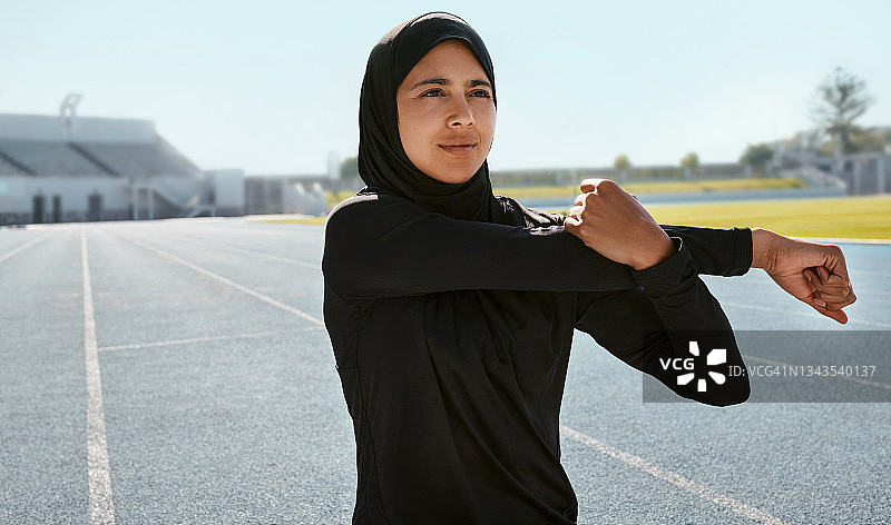 一名年轻女子戴着头巾在跑道上训练图片素材