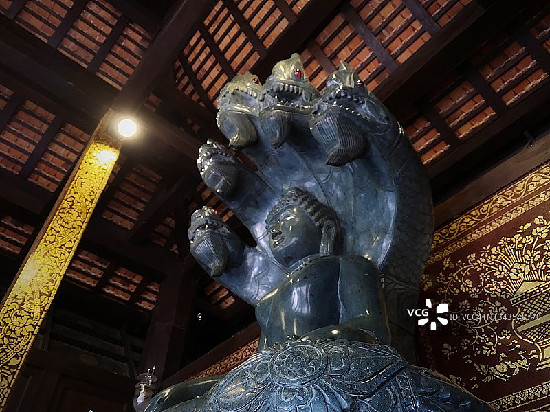 美丽的黑色佛像，佛陀被神秘的蛇(那迦)的头罩保护，在泰国寺庙的大厅里。图片素材