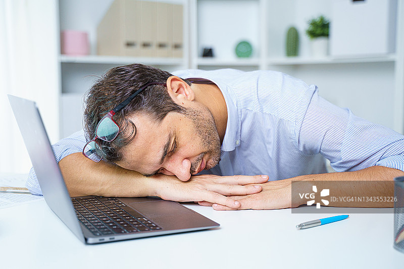 一个效率低下的懒工人在工作场所睡觉图片素材