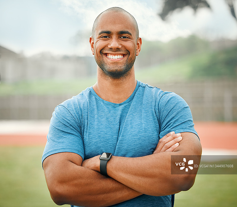 一个英俊的年轻男性运动员的裁剪肖像站在外面，双臂交叉图片素材