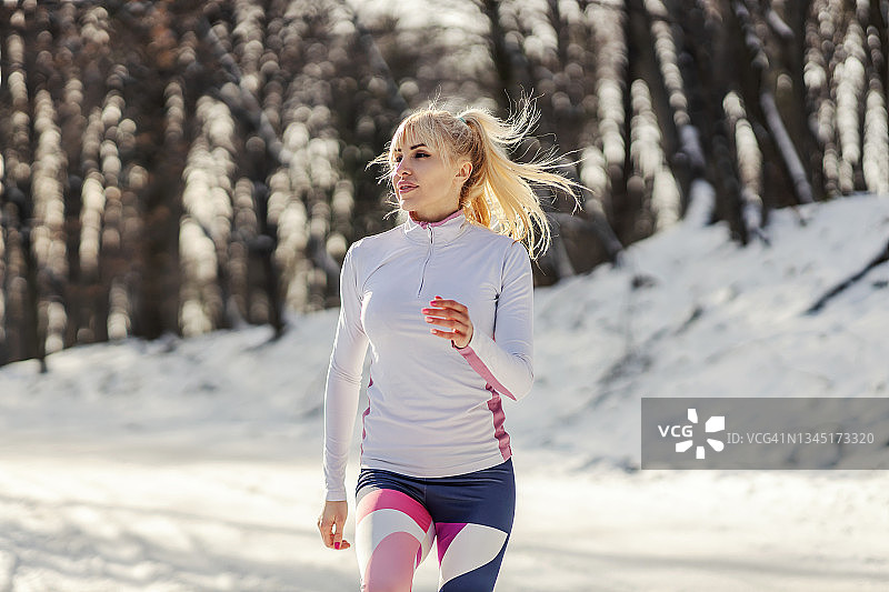 健康的女运动员在雪天在大自然中慢跑。有氧运动，自然健身，冬季运动图片素材