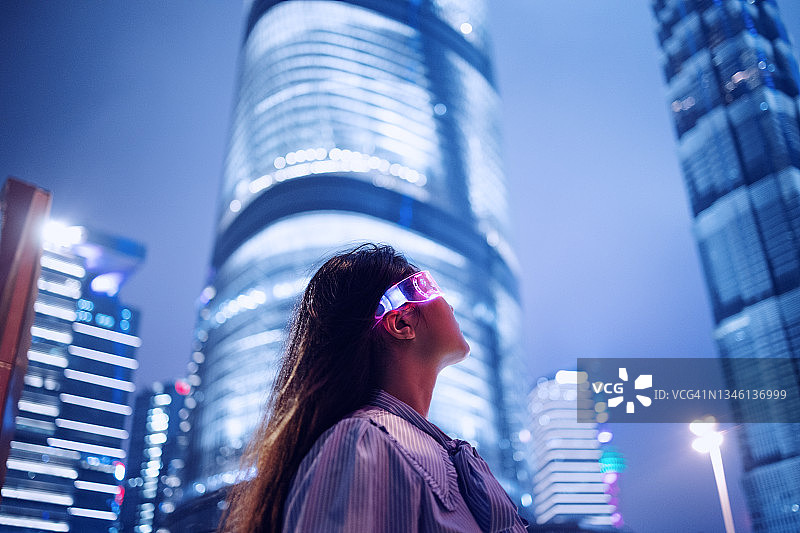在市中心的金融区，年轻的女商人站在现代的金融摩天大楼前图片素材