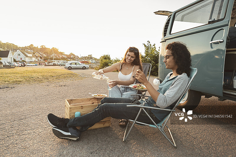 年轻夫妇晚上在露营车外面吃东西图片素材
