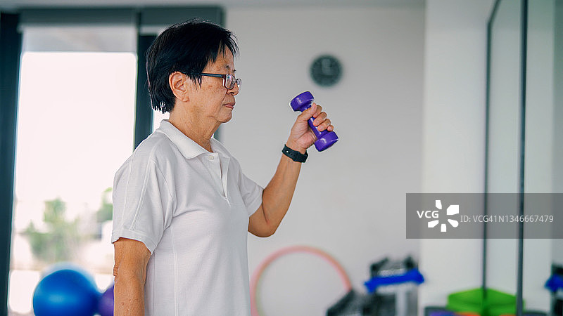 一位年长的女士在健身房锻炼。图片素材