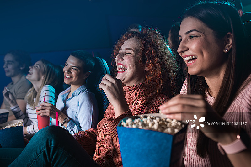 一群兴高采烈的人在电影院看电影时大笑。图片素材