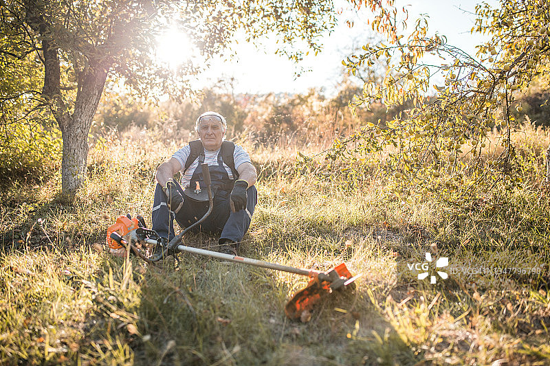一位退休老人坐在院子里的草地上图片素材