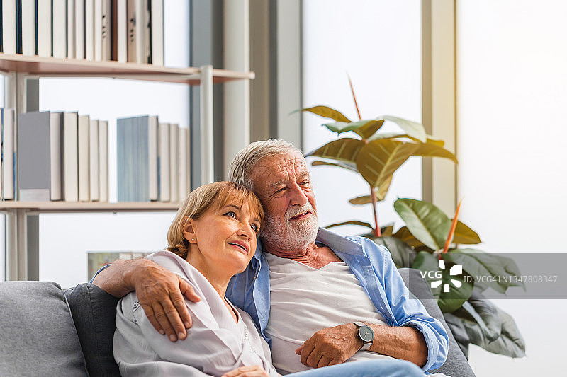 幸福的老夫妇在客厅，老女人和男人放松在舒适的沙发在家里，幸福的家庭概念图片素材