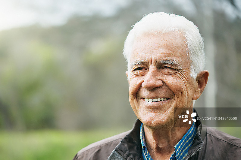 一位70多岁的英俊男子在户外愉快地微笑，一幅幸福和满足的画面图片素材