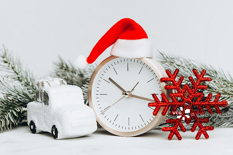 带着圣诞帽的模拟时钟，玩具车和红色雪花图片素材