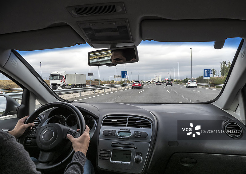 汽车角度，一个年轻人在交通繁忙的双车道公路上开车图片素材