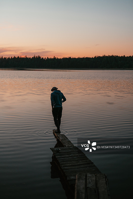 一个人站在湖上的木墩上。田园风景图片素材