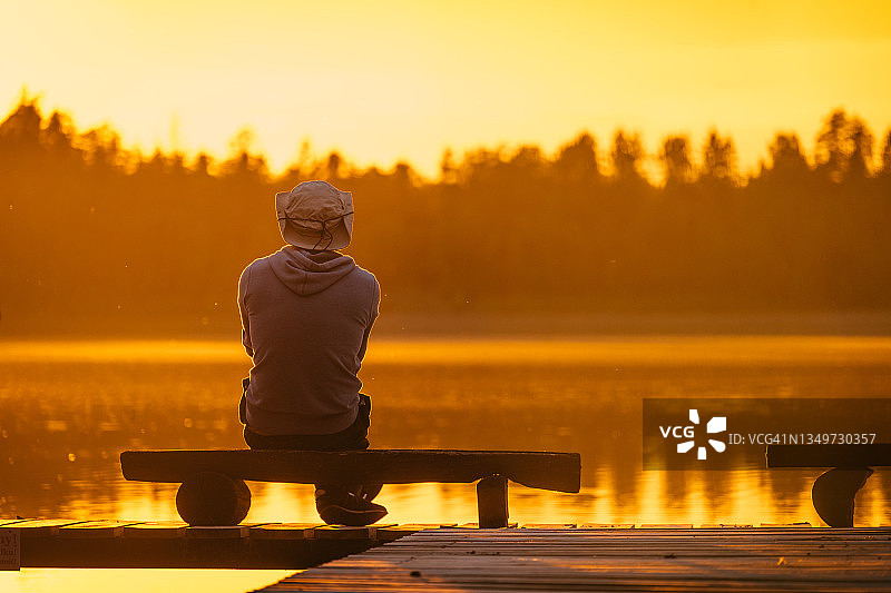 一个男人在湖上的木码头上休息。田园风景图片素材