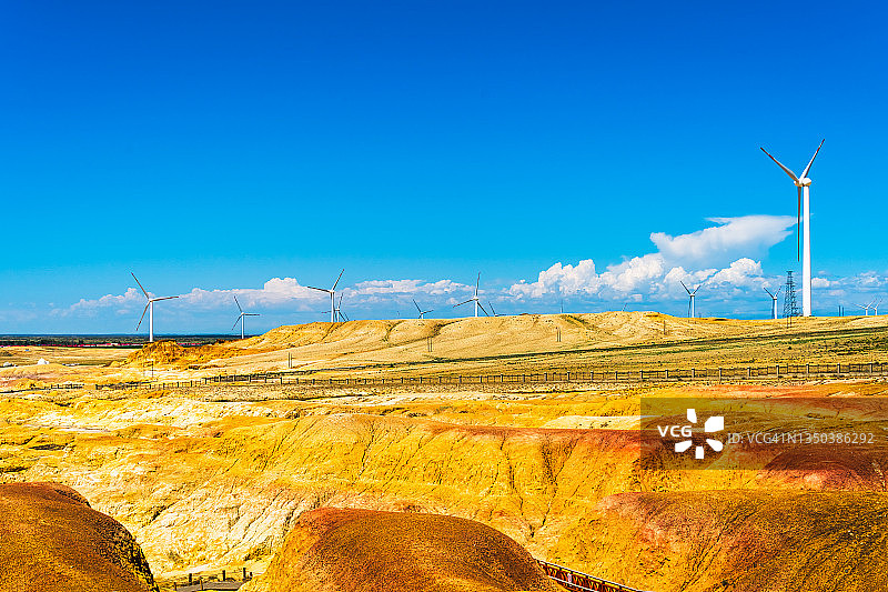 在沙漠的边缘，黄色的岩石裸露在外。风力涡轮机屹立在沙漠中。中国新疆维吾尔自治区。图片素材