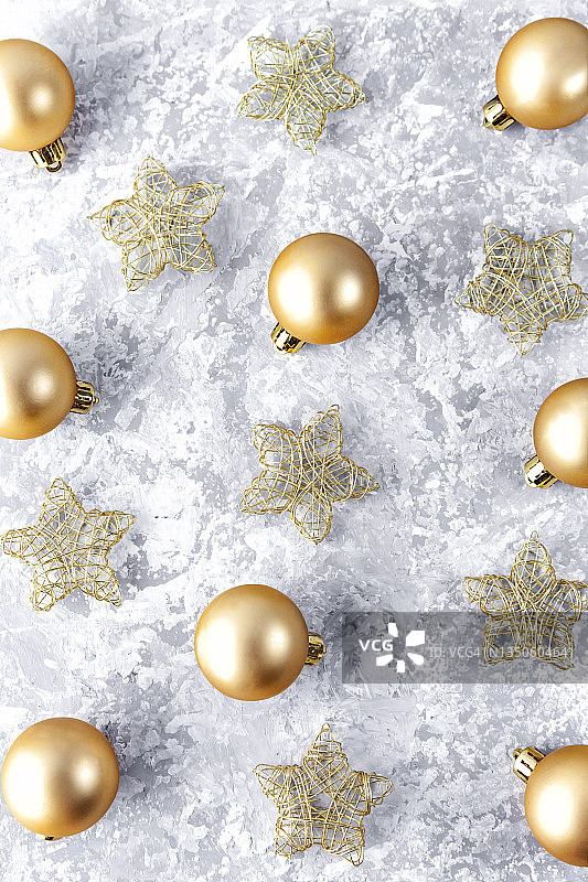 正上方是金色的圣诞球和星星，由金色的黄铜线组成，在灰色的背景上。圣诞节和新年的概念。图片素材