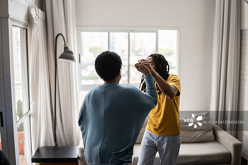 母亲和儿子在家里的客厅里跳舞图片素材