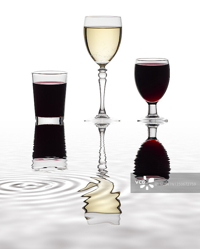 一杯红酒和白葡萄酒，倒映在水面上。图片素材