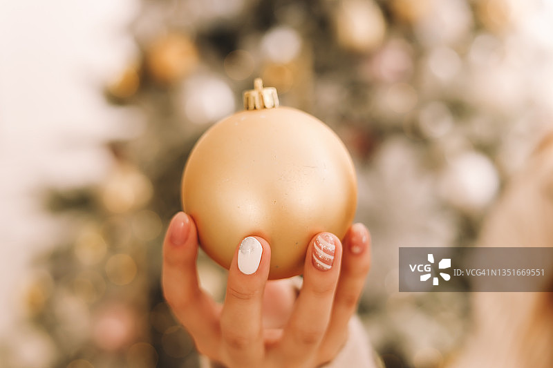 女人的手修得很好，穿着舒适的毛衣，正在为圣诞节做准备，用气球和玩具装饰圣诞树，打开新年家里的节日礼品盒图片素材