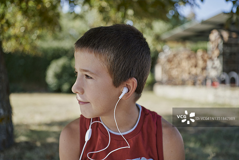 一个可爱的男孩一边听音乐一边看别处图片素材