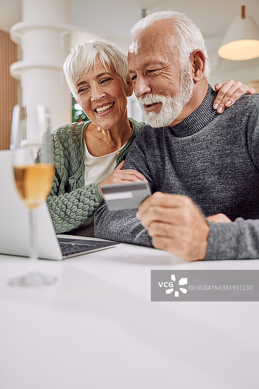 快乐的老夫妇用笔记本电脑和信用卡在网上购物图片素材
