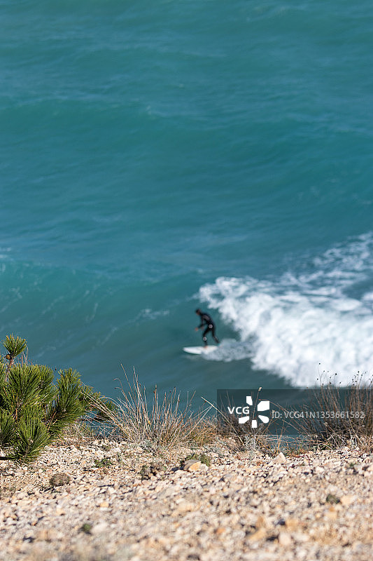 冲浪者在蓝色的波浪上冲浪，前面是海岸线图片素材