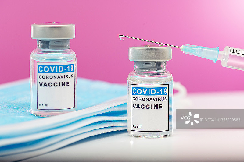 冠状病毒Covid-19疫苗。注射器靠近玻璃瓶和面罩。图片素材