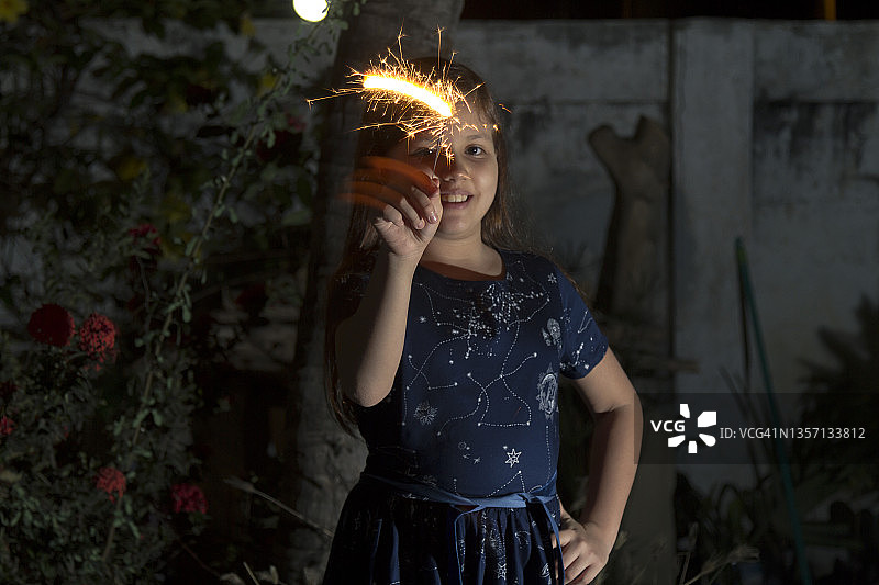 拉丁美洲厄瓜多尔，年轻的拉丁小女孩在外面庆祝新年或圣诞节，玩烟花。

厄瓜多尔新年前夕的流行传统。图片素材