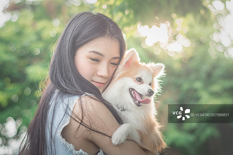 一名年轻的亚洲女子正在泰国曼谷的公园里和心爱的狗狗玩耍图片素材