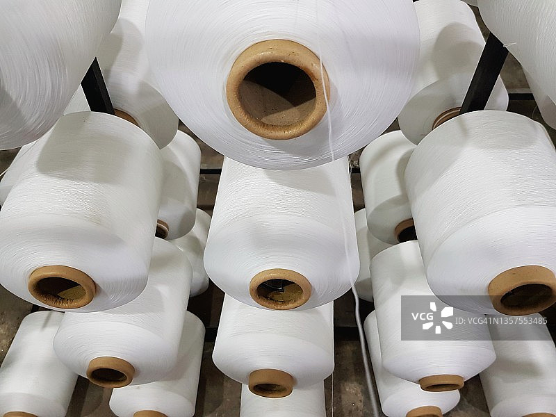 在纺织厂的整经机上的一组大的白色线锥。图片素材