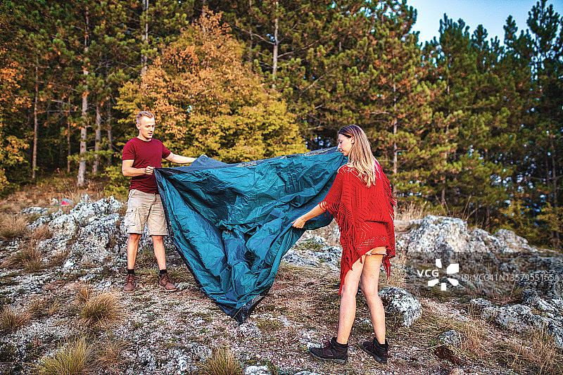 一对年轻夫妇在山上搭帐篷图片素材