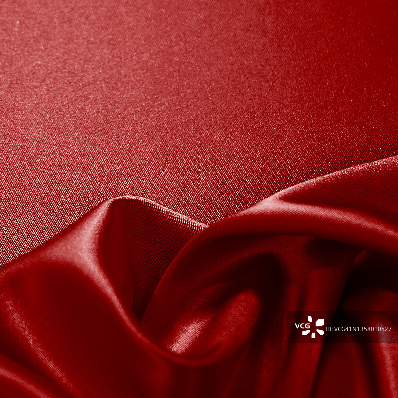 鲜红丝绸缎子天鹅绒。美丽柔软的波浪褶皱。特写镜头。闪亮的织物背景图片素材