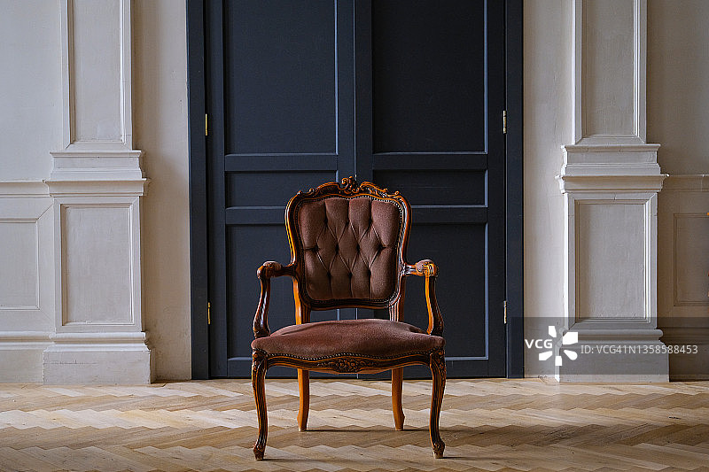 米色天鹅绒椅子靠在客厅的黑色门上。复古风格的室内装饰。图片素材