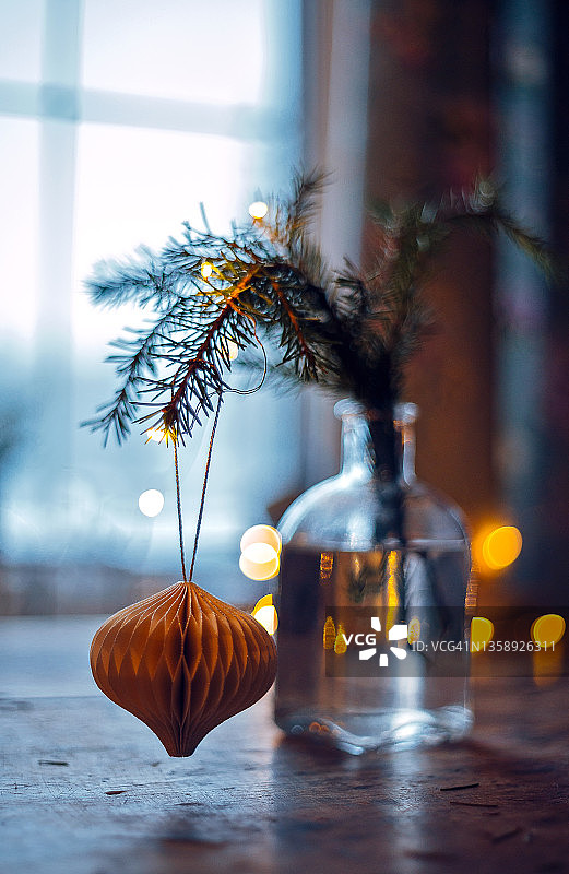 圣诞冷杉树枝与古董纸装饰玩具在透明瓶附近的窗口。散景花环图片素材