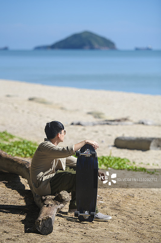 亚洲男子与冲浪休息在海滩上图片素材