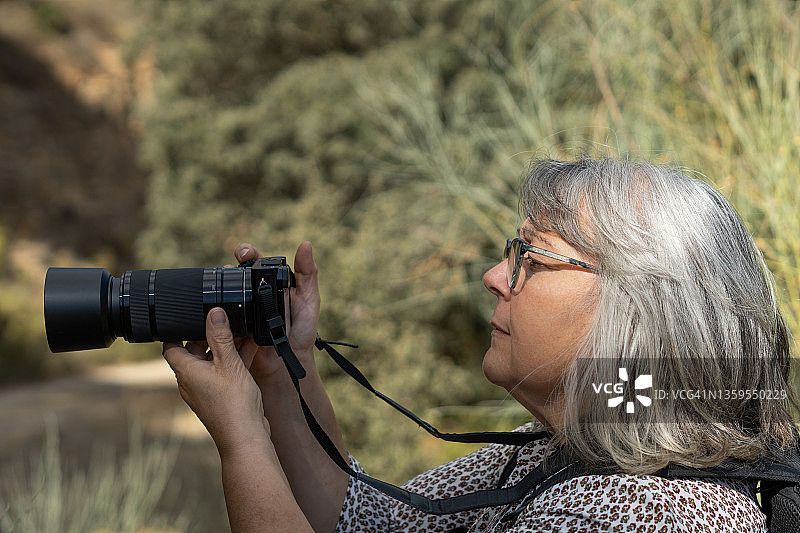 白发苍苍的老妇人在森林里拍照图片素材