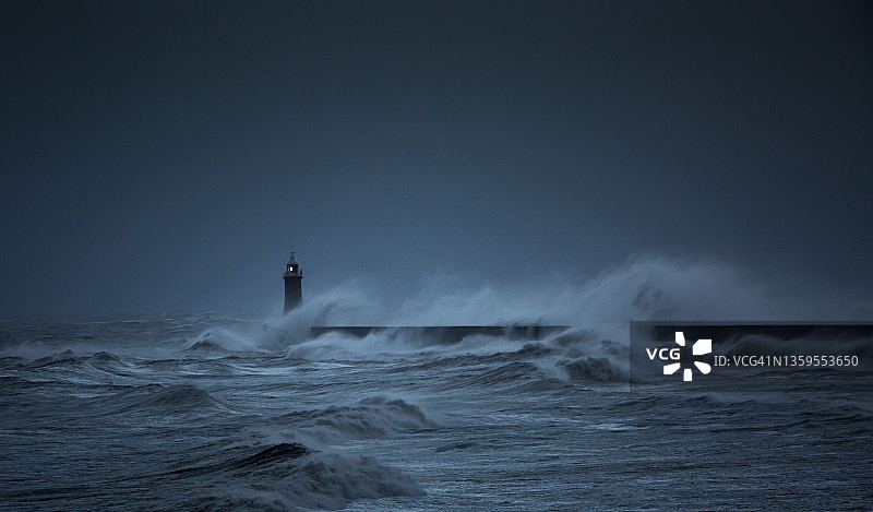 风暴亚文袭击了英国泰恩茅斯的海岸线，强风中巨浪冲击着灯塔图片素材