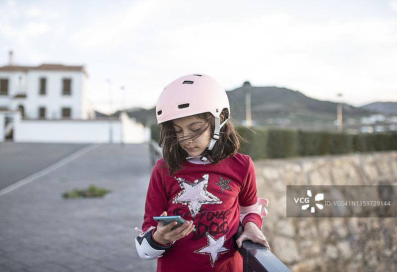 滑冰女孩在休息时，一边做着她的活动，一边看着她的智能手机图片素材