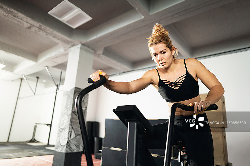 白人女性，在现代健身房的固定自行车机上锻炼图片素材