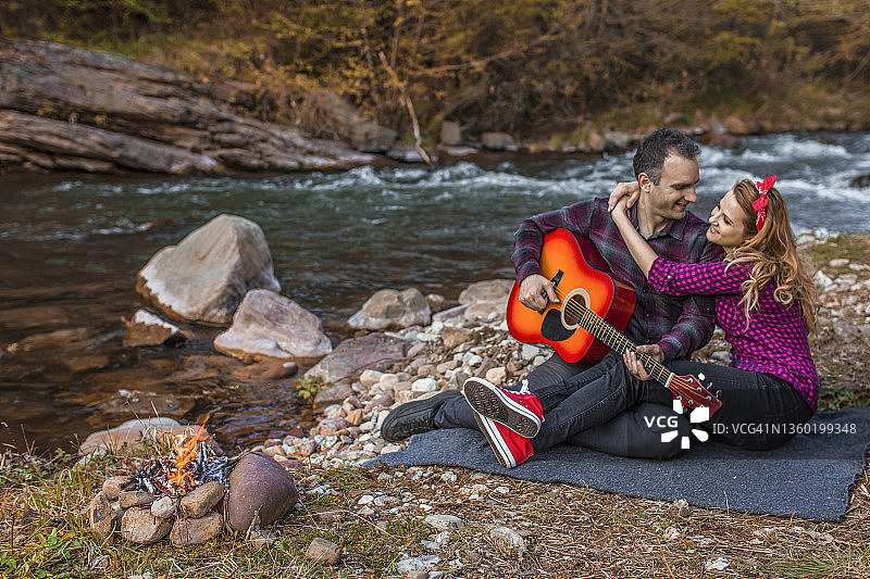 浪漫的男朋友在河边为女朋友弹吉他图片素材