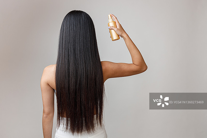 黑发年轻女子在头发上喷发胶图片素材