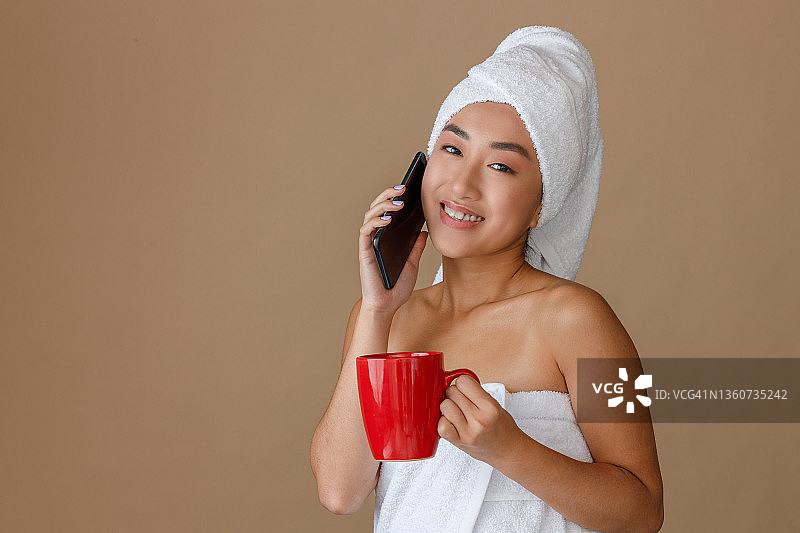 快乐的亚洲女人在淋浴后打电话图片素材