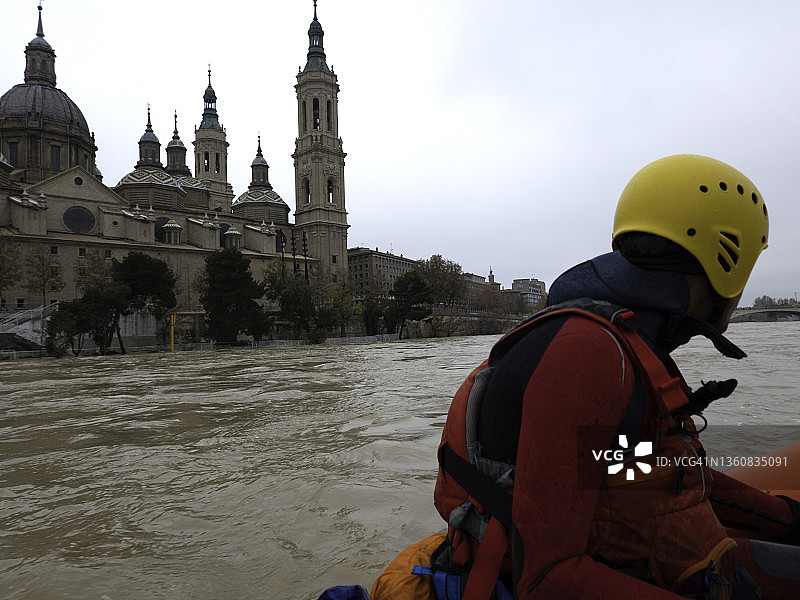 救援人员驾驶着船沿着城市旁边的河航行图片素材