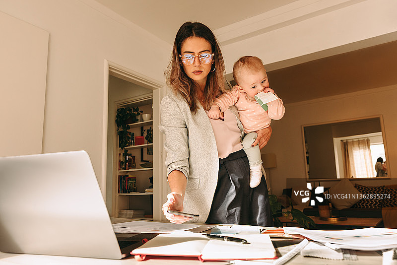 女性室内设计师抱着她的孩子在她的家庭办公室图片素材