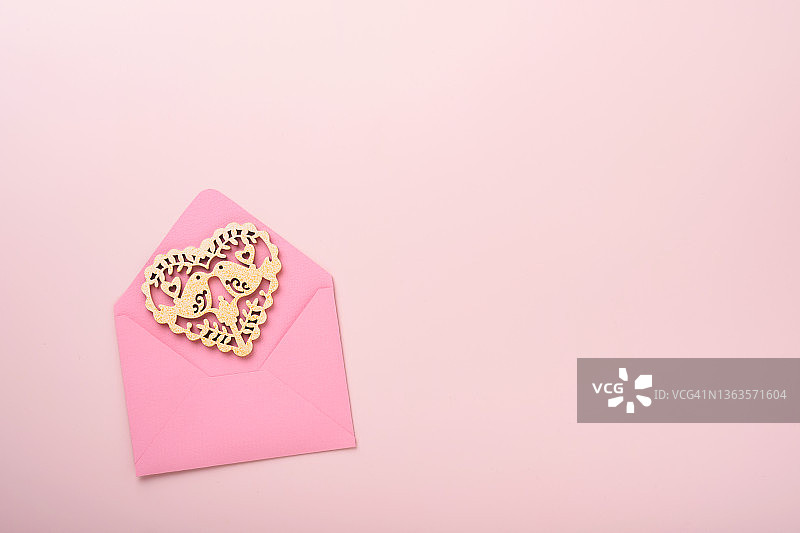 粉红色信封与白色开放的心和红色丝带在粉红色的背景。顶部视图与复制空间。情人节或婚礼的浪漫概念。节日的作文。模拟。图片素材