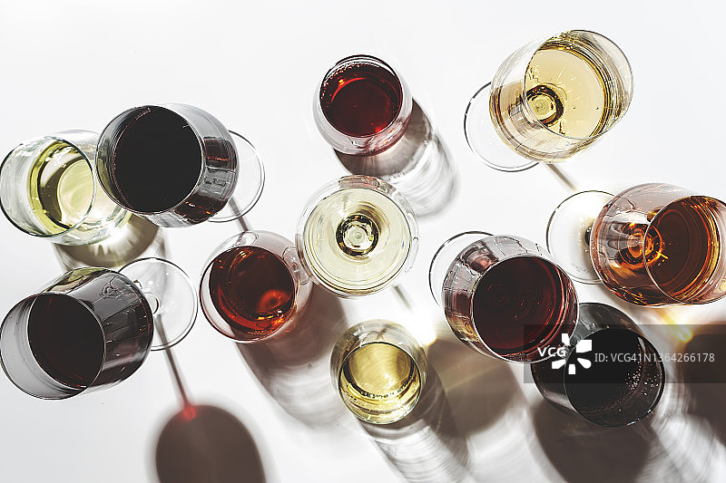 红，白，玫瑰葡萄酒在玻璃杯在白色背景的分类，俯视图。酒吧、商店、酒庄、户外品酒理念。强光和阴影图片素材