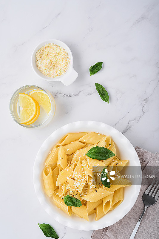 美味可口的经典意大利通心粉与帕尔马干酪和罗勒在白色的盘子在石头桌子上盘子。意大利传统菜肴。前视图。图片素材