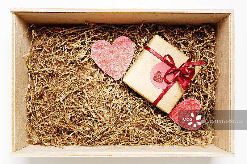 木盒与礼物包裹在棕色牛皮纸红色丝带，充满纸填料，俯视图图片素材