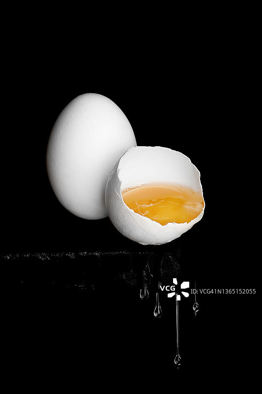 带着蛋黄的鸡蛋掉在一块黑石头的边上。图片素材