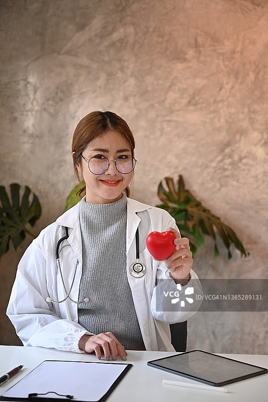 年轻漂亮的女医生手里拿着一颗红心。医疗保健和医疗概念。图片素材