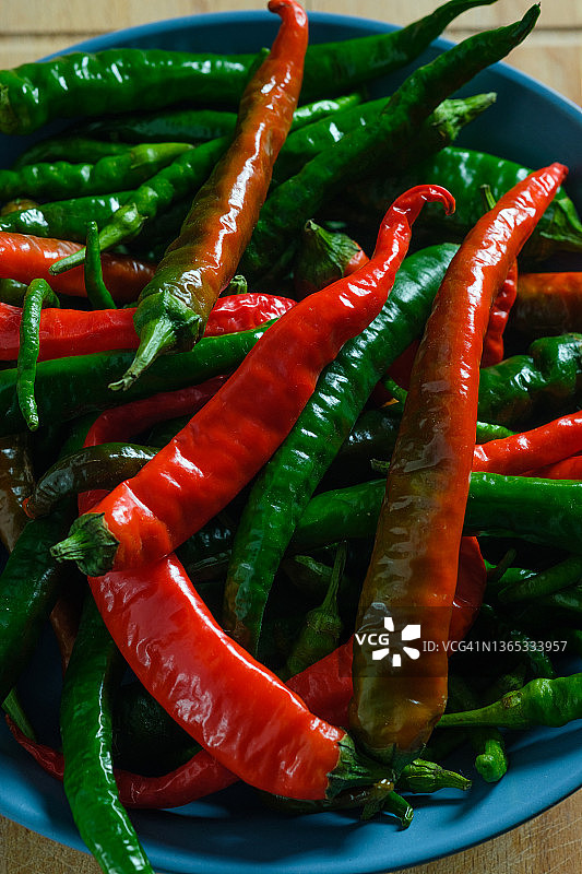 红色和绿色的熟的和未熟的辣椒放在木制背景或厨房桌子上。种植有机农产品。烹饪，为美食家准备的香料。图片素材