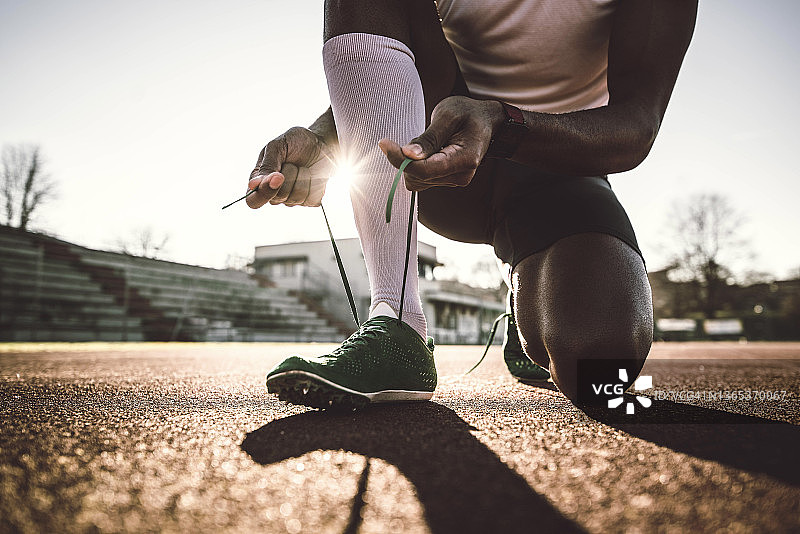 男子尝试慢跑鞋特写-男性运动员在体育场的跑道上跑步-运动生活方式的概念图片素材